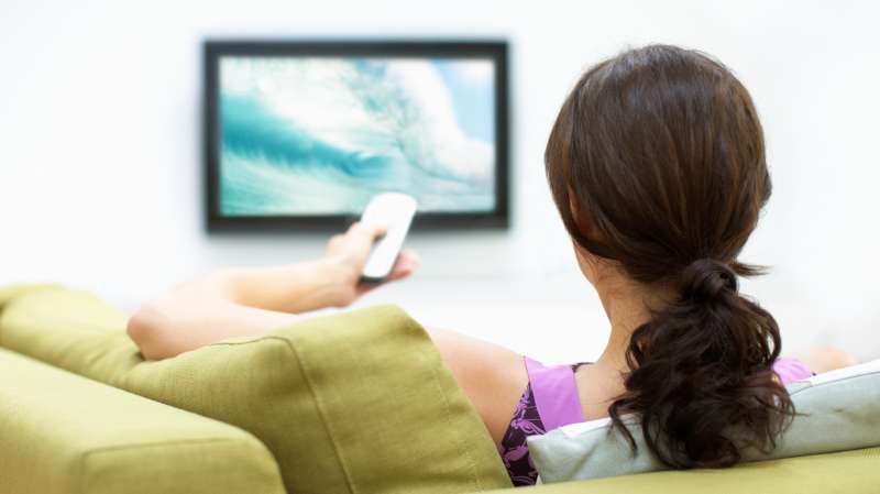 Young woman watching television, rear view