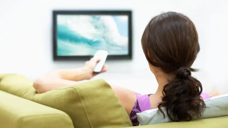 Young woman watching television, rear view