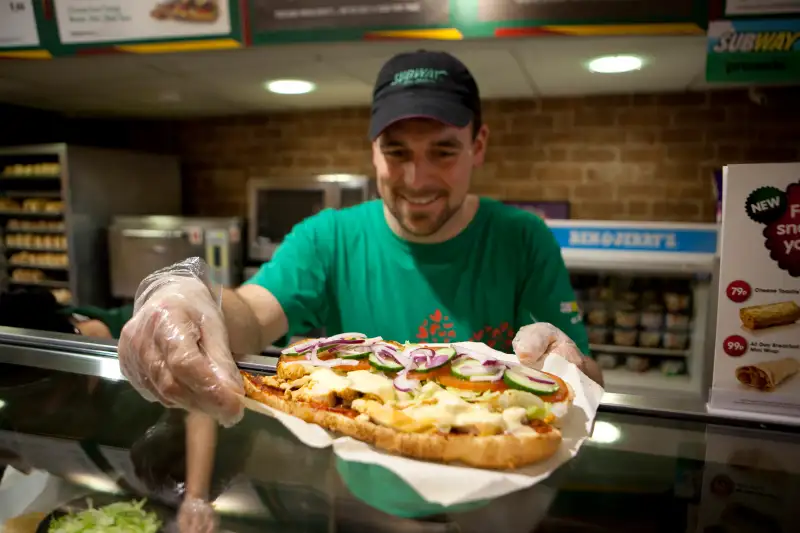 A member of staff preparing a footlong 'sub'.