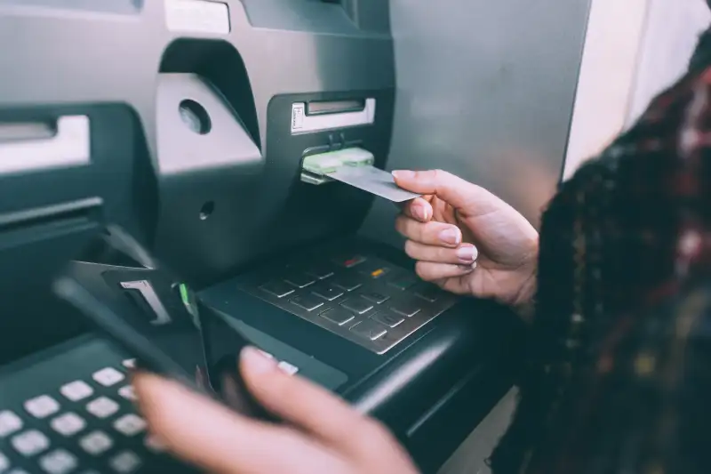 Hand of young woman inserting credit card into cash machine