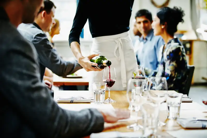 Waitress pouring wine into glass at table