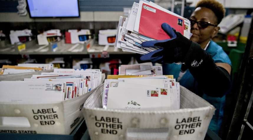 A worker places mail into a tray next to an advanced face cancelling machine at the United States Postal Service (USPS) Suburban processing and distribution center in Gaithersburg, Maryland, U.S., on Tuesday, Dec. 19, 2017.