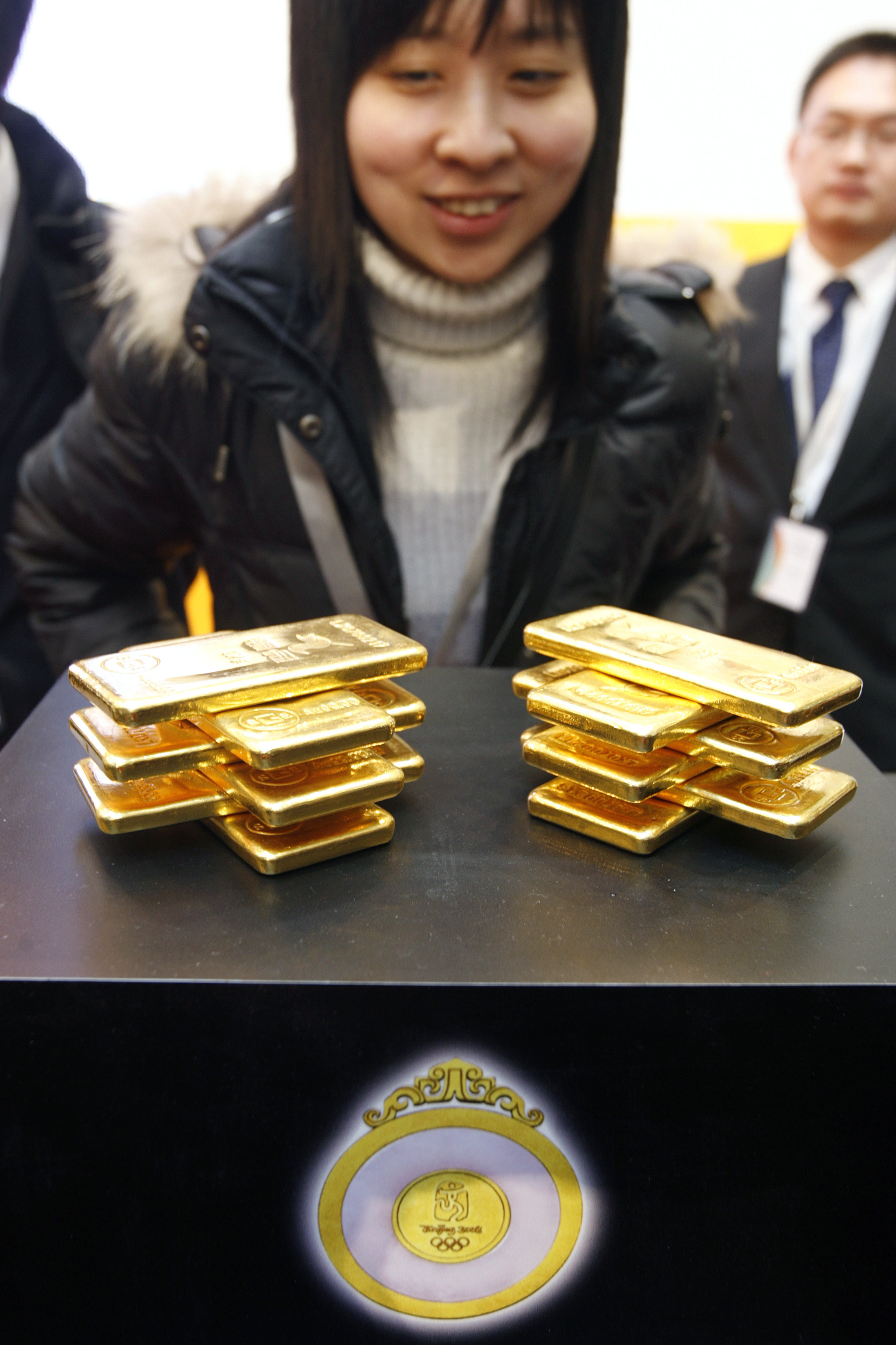 A woman looks at gold bars during a handover ceremony in Shanghai