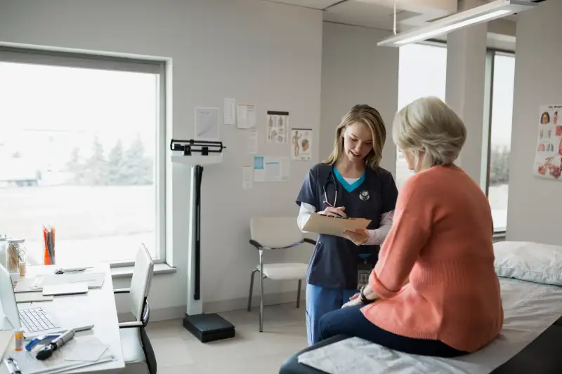 Nurse writing on patients medical chart in clinic