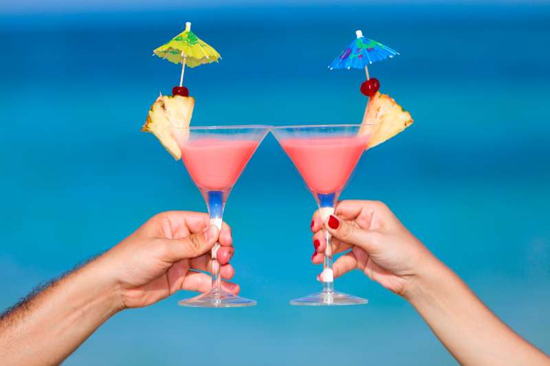 Couple toasting with tropical drinks on a turquoise beach