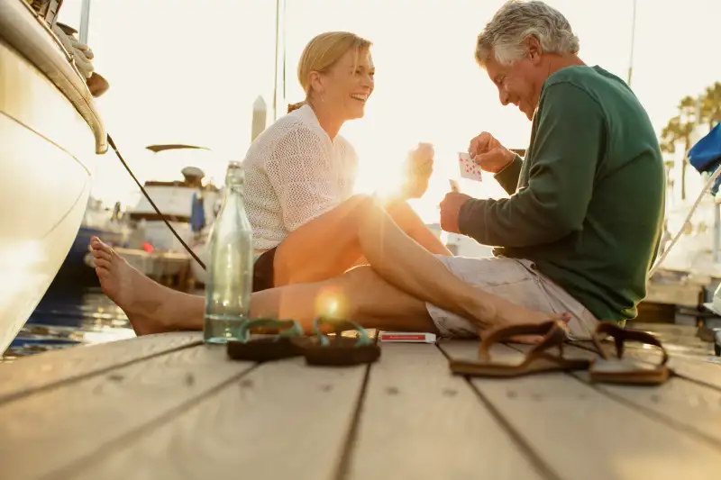 Couple sitting on marina pier playing cards, Redondo Beach, California, USA