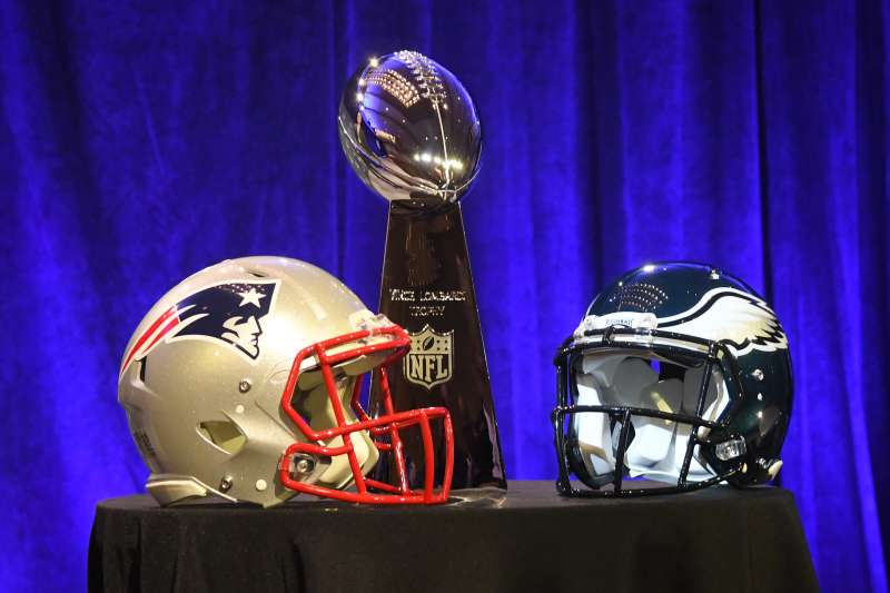 The Vince Lombardi Trophy and helmets from the New England Patriots and Philadelphia Eagles are displayed at a Super Bowl LII press conference.