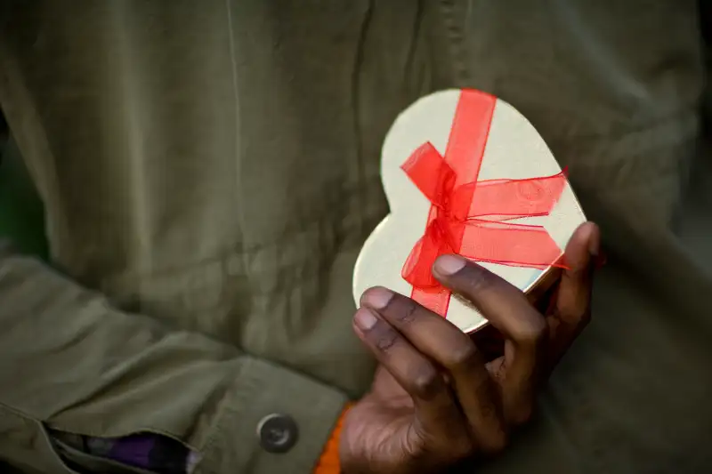 A close up of a heart shaped gift hidden behind a mans back in the Winter Wonderland at Hyde Park, an event organised for 'family, friends and colleagues to delight in the magical atmosphere of London' during Christmas 2007., Hyde Park, London, London, Eng