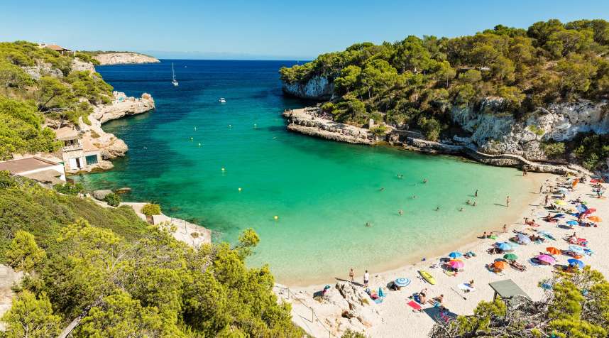 Sunbathers enjoy the beach at Cala Llombards on Mallorca.