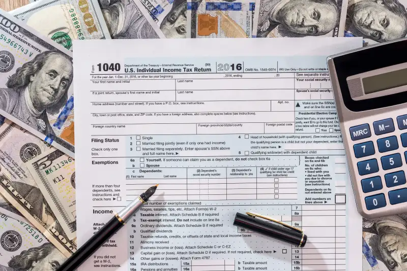 1040 tax from with us dollar banknote, pen and calculator.