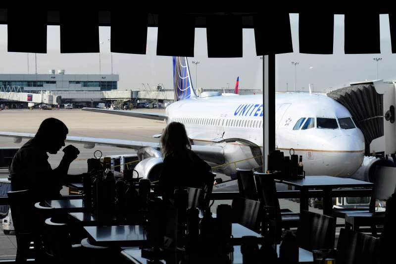 Airline passengers eat in a terminal cafe as a United Airlines passenger plane is parked at a gate at Denver International Airport in Denver, Colorado.