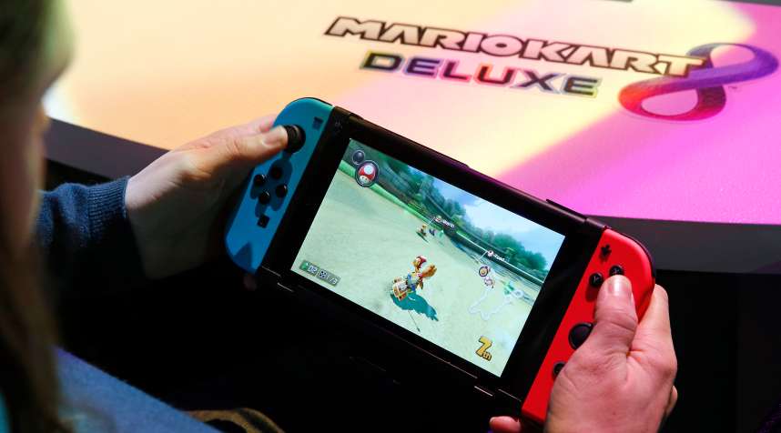 A visitor plays the  Mario Kart 8 Deluxe  video game on a Nintendo Switch games console during the new console's unveiling by Nintendo Co on January 13, 2017 in Paris, France. This next-generation game console, billed as a combination of a home device experience and a portable entertainment system, will be available for $ 299.99 in the US from March.