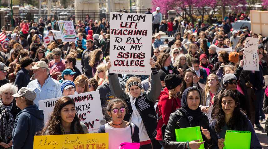 Teachers and demonstrators hold signs during a strike outside the Oklahoma State Capitol building in Oklahoma City,  on April 3, 2018.