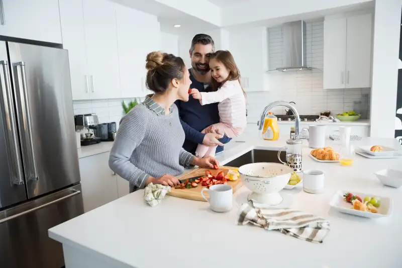 Daughter feeding mother fruit in kitchen