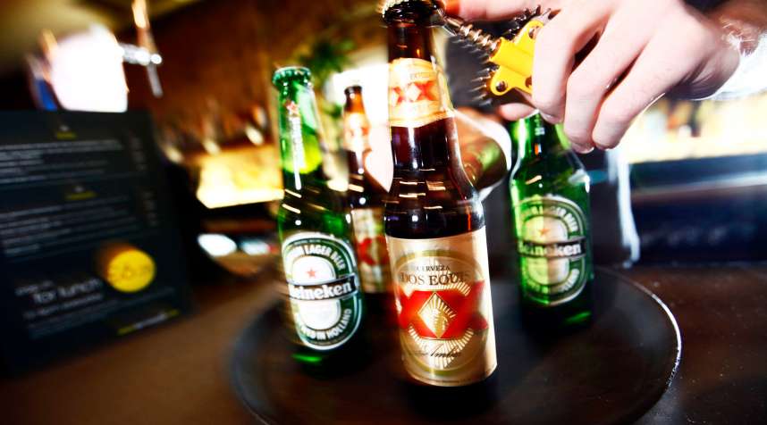 A barman opens a bottles of Dos Equis and Heineken beer at a public house in London, U.K., on Monday, Jan. 11, 2010.