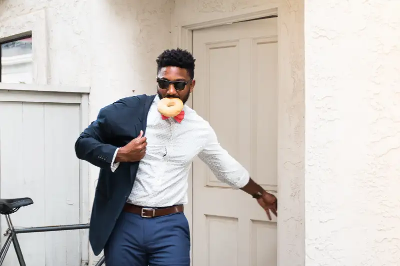 Young businessman eating doughnut and closing front door