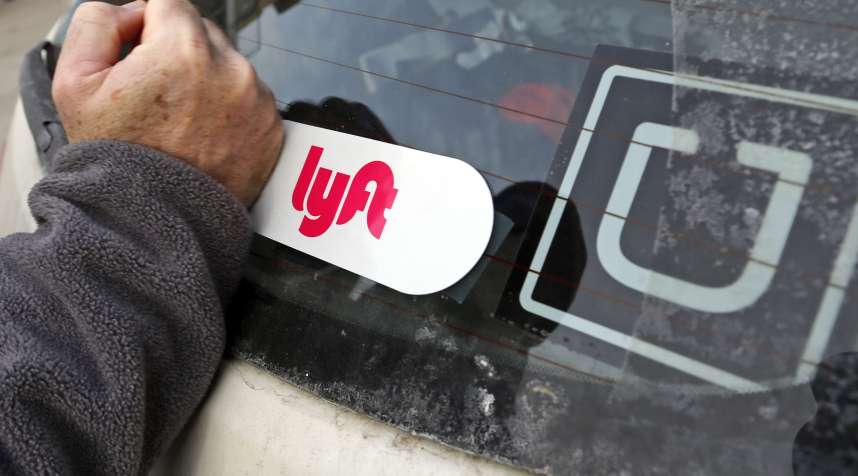 This is a Lyft logo being installed on a Lyft driver's car who also drives for Uber on in Pittsburgh, January 31, 2018.