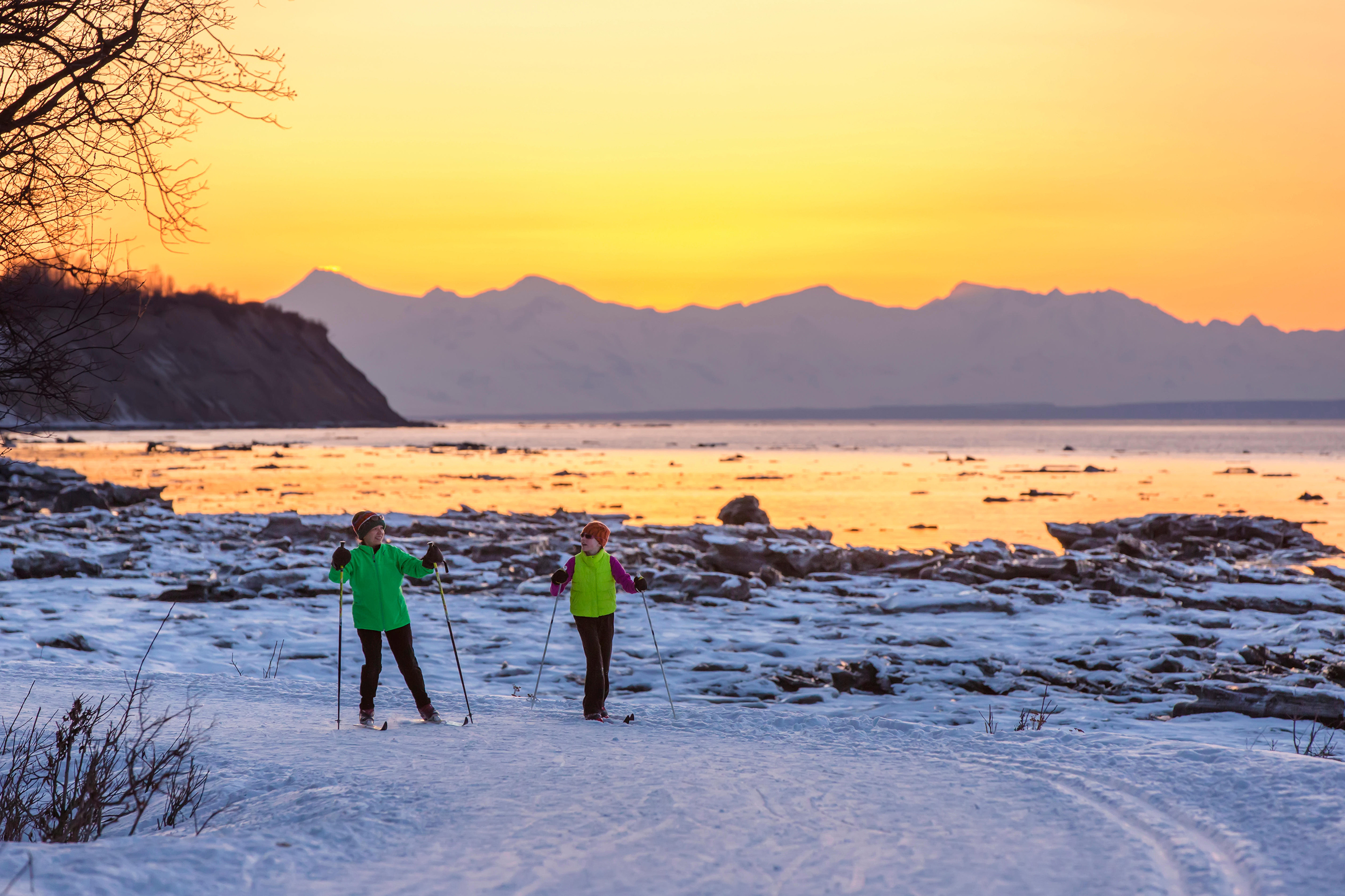 Two people cross country skiing on the Tony Knowles Coastal Trail at sunset, Southcentral Alaska