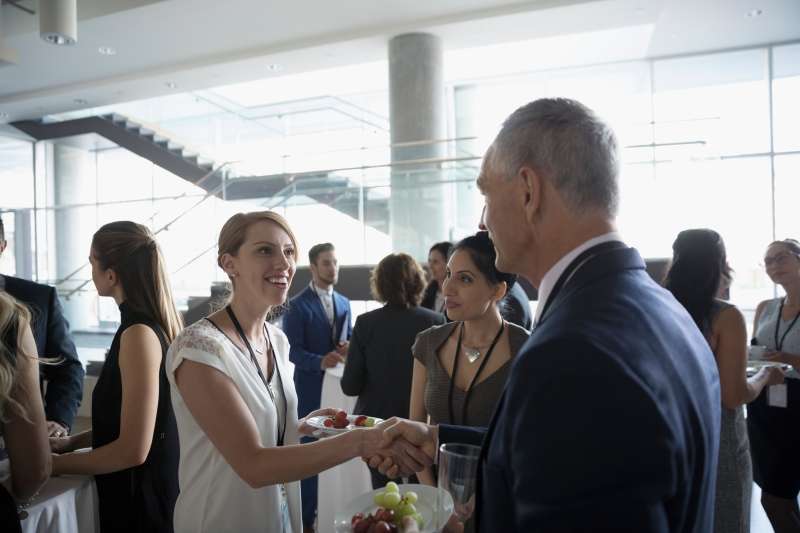 Business people handshaking, networking and eating at conference
