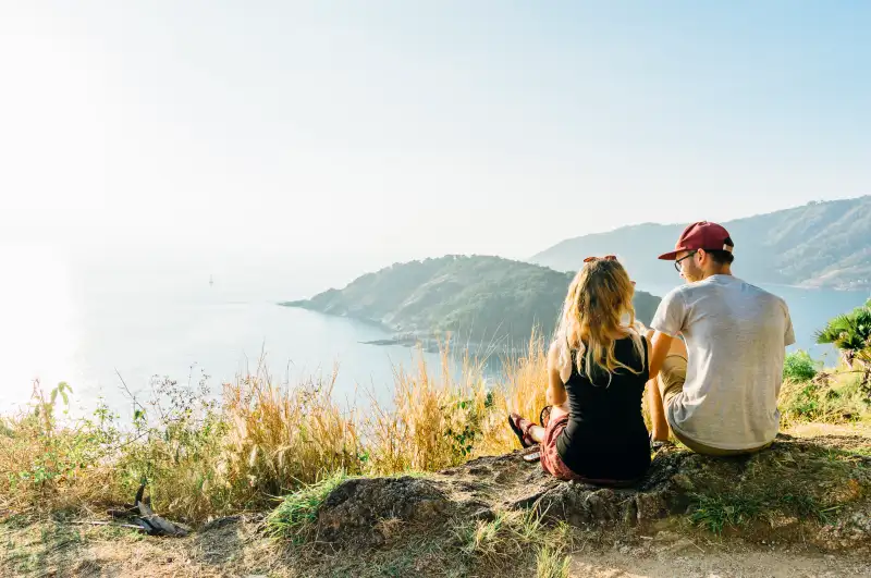 Young couple relax, on hillside above sea