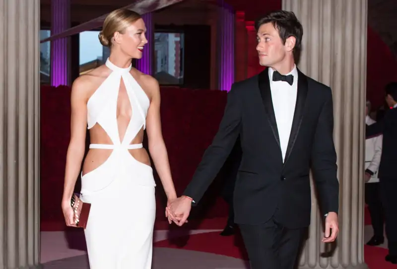 The couple holds hands, looking at each other, while dressed in formal attired at an event