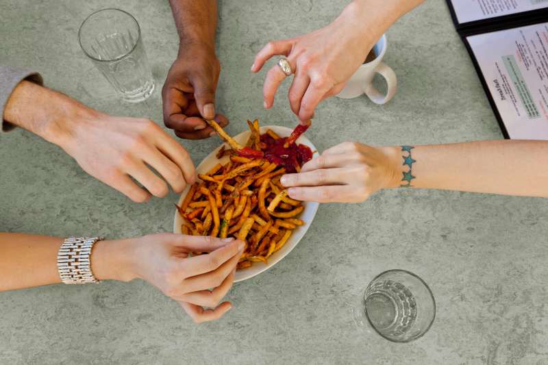 Close-up of hands with French fries in diner