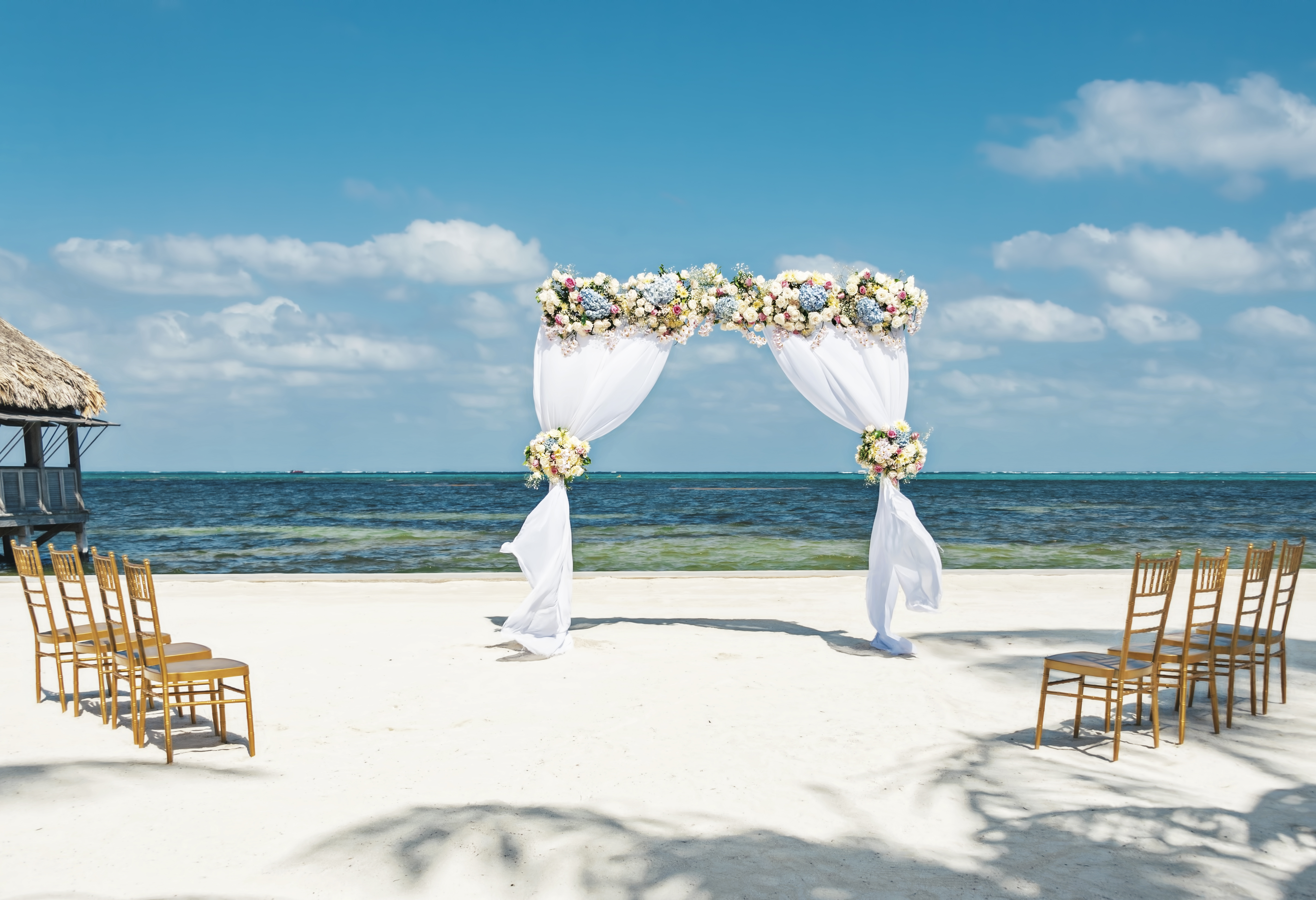 Fresh flower arbor on the beach with eight chairs for a small beach wedding