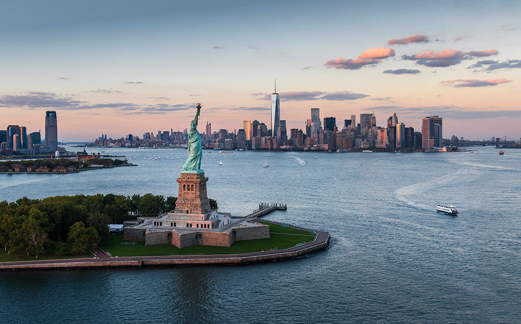 Aerial view of city with Statue of Liberty at sunset