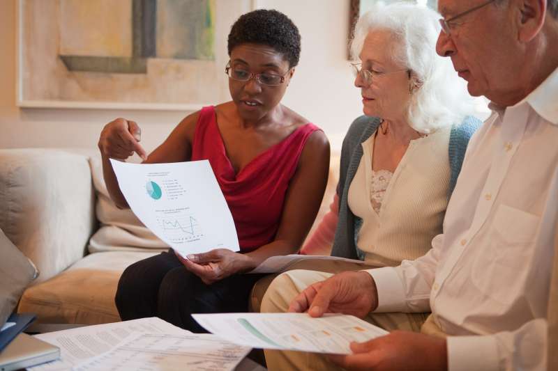 Mid adult woman showing financial paperwork to senior couple