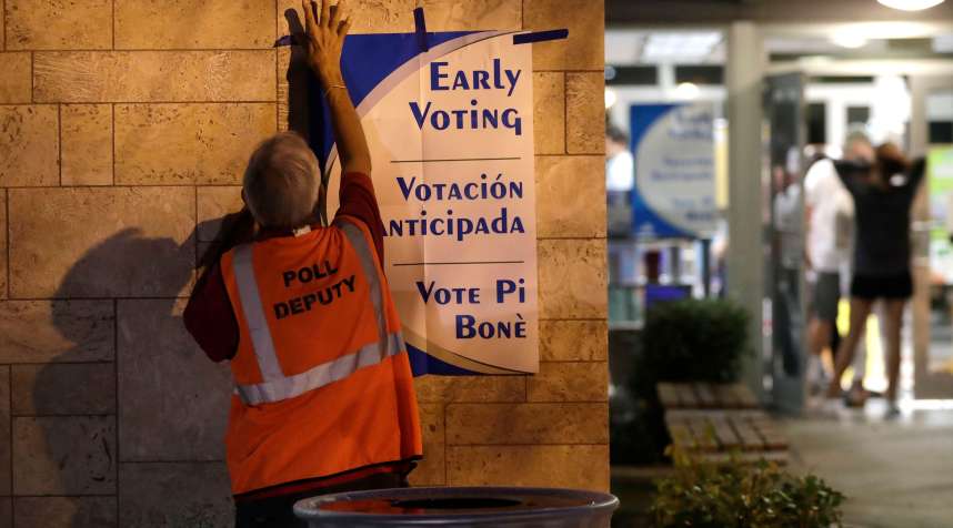 A poll worker hangs a sign at a polling station on the first day of early voting in Miami-Dade County, in Miami, October 22, 2018.