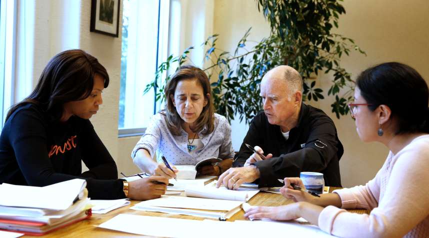 Gov. Jerry Brown reviews a measure with his wife, Anne Gust Brown, second from left, as staff members Camille Wagner, left, and Graciela Castillo-Krings, right, look on at his Capitol office, Sunday, Sept. 30, 2018, in Sacramento, Calif. Sunday is the last day for Brown to approve or veto bills passed by the legislature. Brown, who will be leaving office in January, is acting on some on the last pieces of legislation in his tenure as governor.