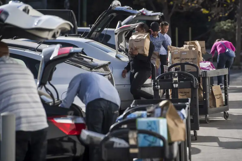 Contractors working for the Amazon Inc. Flex program load packages into vehicles to deliver to customers in San Francisco, California, on Oct. 30, 2018.