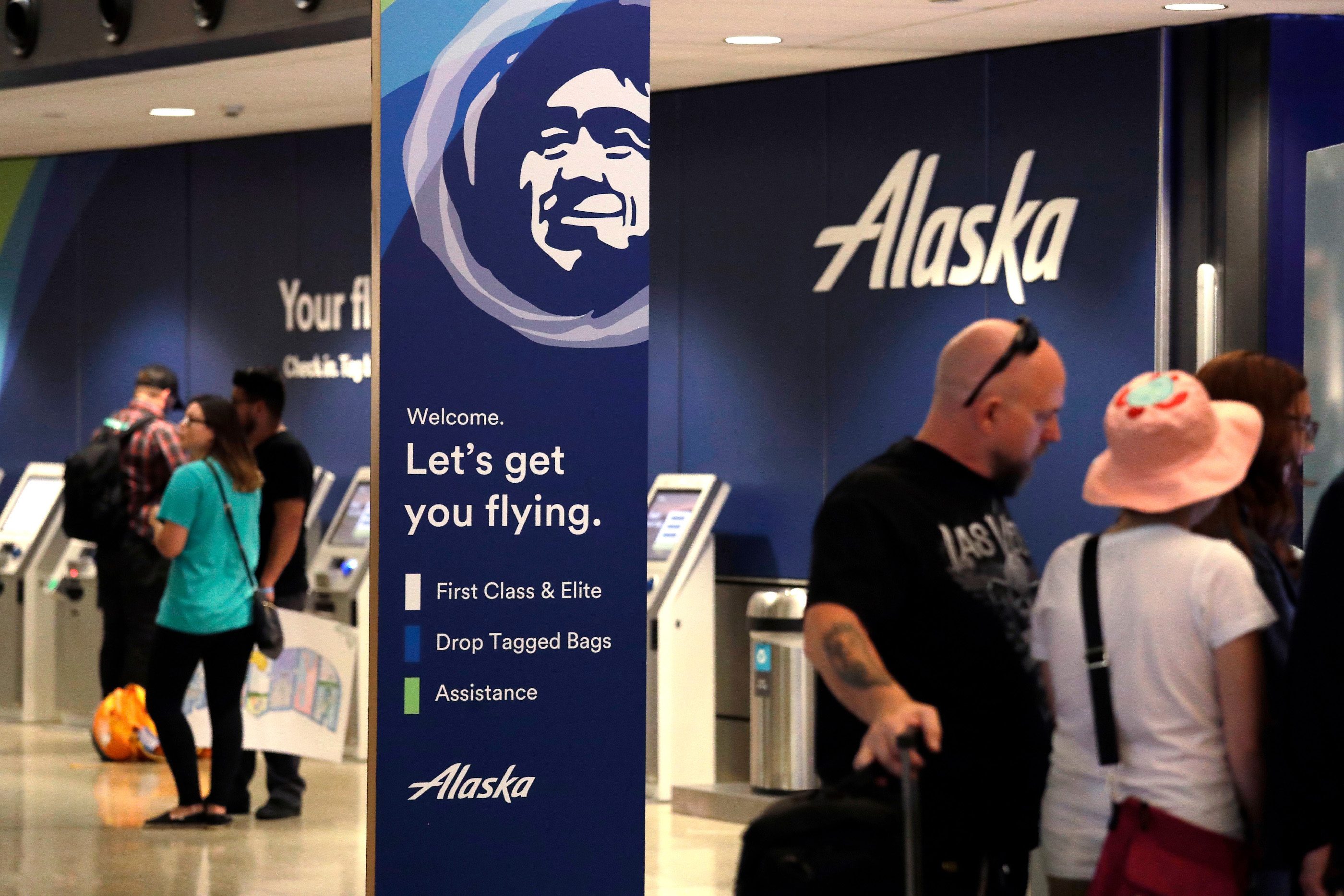 People stand in the Alaska Airlines ticket area at Sea-Tac International Airport, in SeaTac, Wash., August 10, 2018.