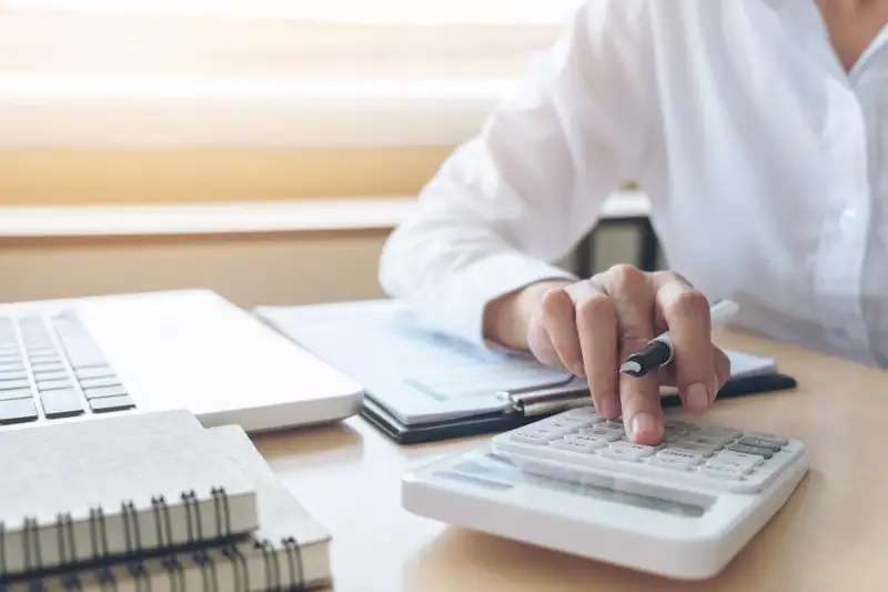 Midsection Of Businesswoman Using Calculator At Desk In Office