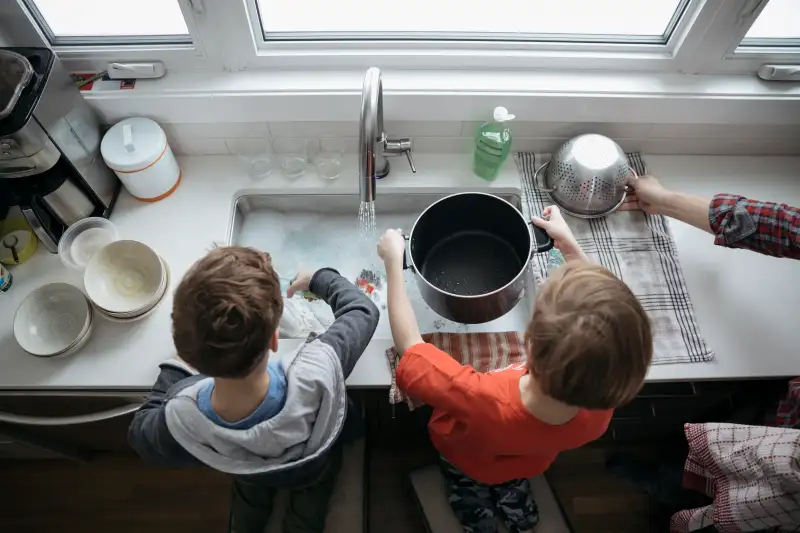 Overhead view brothers doing dishes at kitchen sink