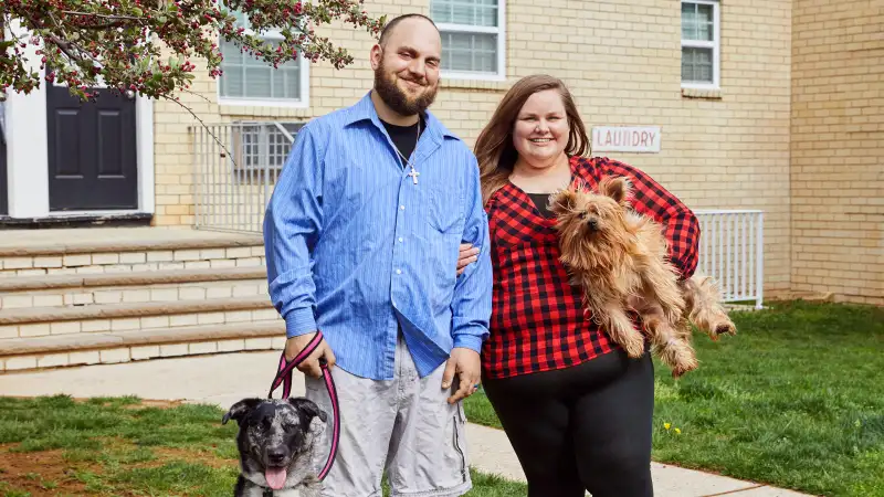 susskinds standing outside an apartment building with their two dogs