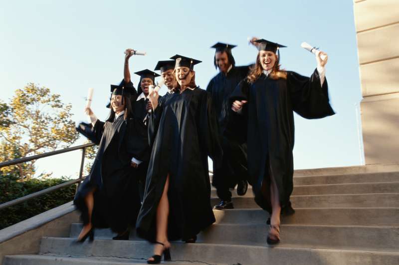 College graduates running down steps