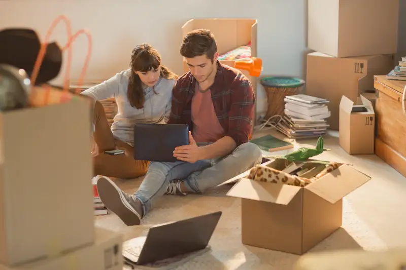 Young couple using laptop surrounded by moving boxes