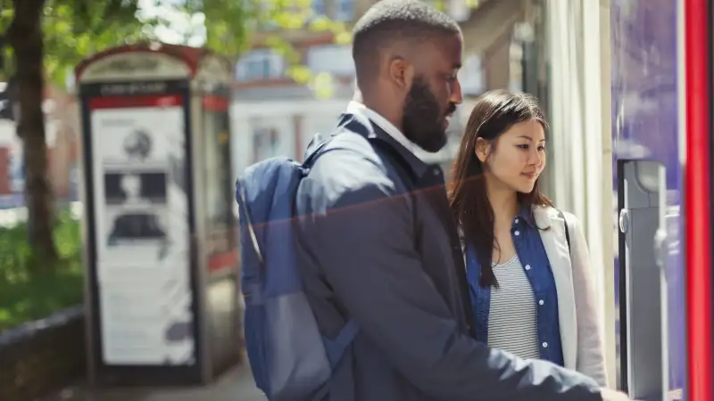 Young couple using urban ATM