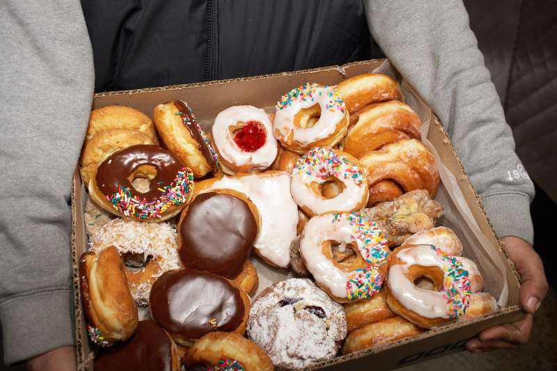 Street vendor carrying box of doughnuts, mid section, elevated view