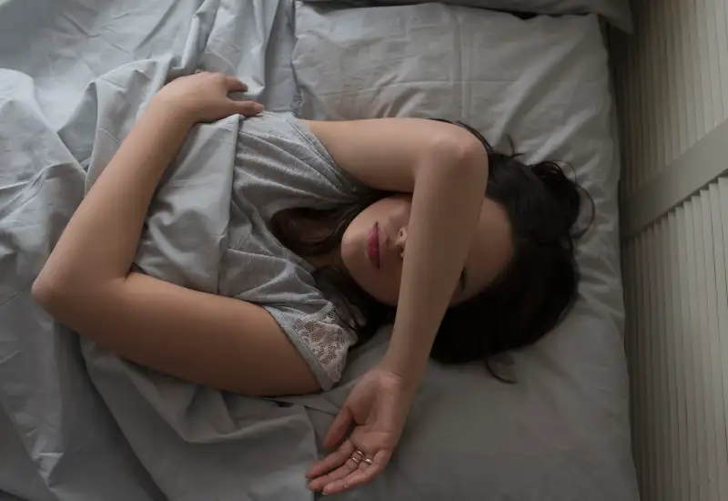 USA, New Jersey, Elevated view of young woman sleeping in bed