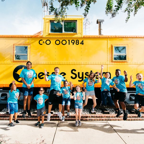 Children in matching shirts in front of bright yellow train caboose in Winter Garden, Florida