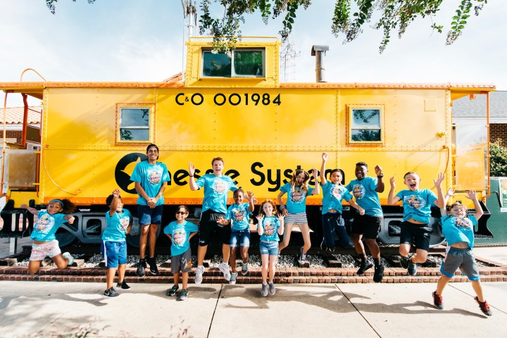 Children in matching shirts in front of bright yellow train caboose in Winter Garden, Florida