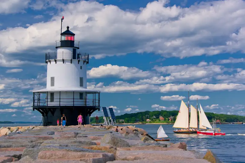 light house and sail boat off the coast of Portland, Maine