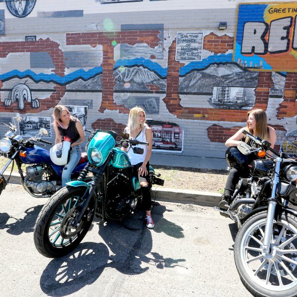 Three women on motorcycles in front of graffiti wall in Reno, Nevada