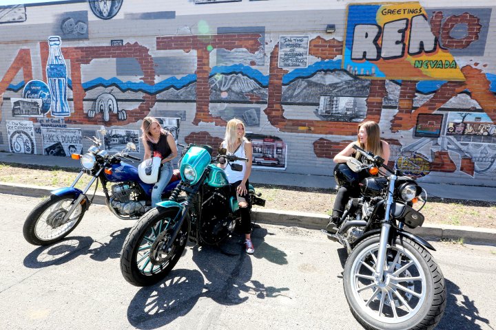 Three women on motorcycles in front of graffiti wall in Reno, Nevada