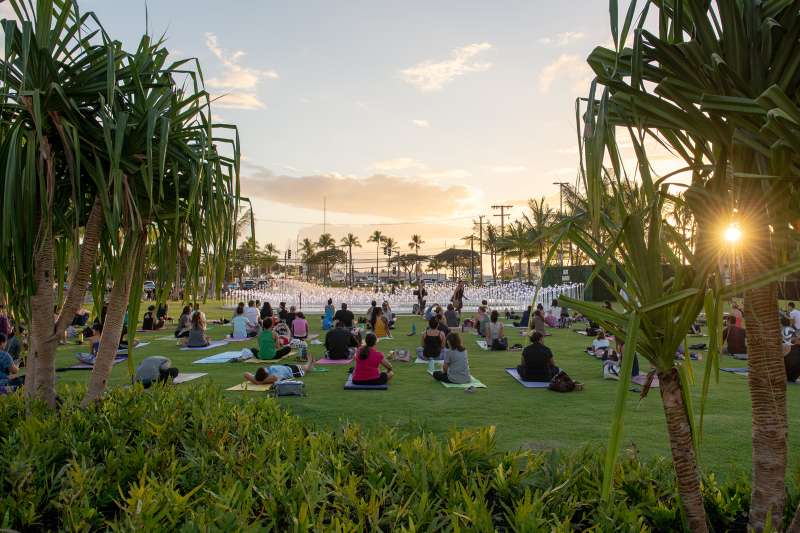 Crowd doing yoga in a park at sunset in Kakaako, Honolulu, Hawaii