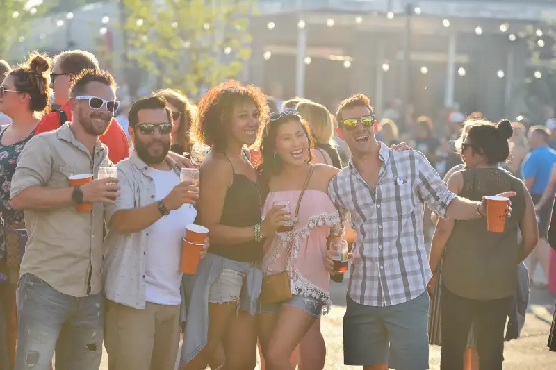 three men and two women gathered for picture with red solo cups of beer