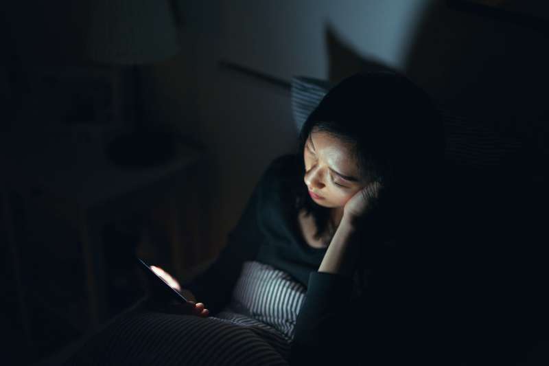 Tired woman fell asleep while using smartphone in bed at night