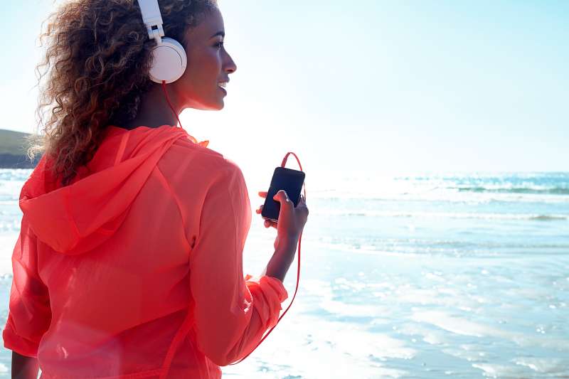 Woman looking out to sea with headphones on.